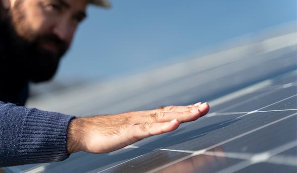 Quanto tempo dura um sistema de energia solar? A imagem de um instalador passando a mão sobre o kit de painel solar instalado